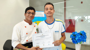 O jovem recebe do professor Ruan Brasil, um dos idealizadores da competição, o certificado de participação no concurso. Foto: Ascom IEPTEC